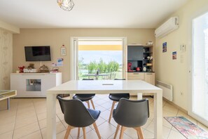 A modern kitchen with a dining table and chairs, a TV, and a view of the outdoors. - Holiday Home 'Les Demeures Du Soleil - Le Ventoux' with Pool, Wi-Fi and Air Conditioning (Piolenc)