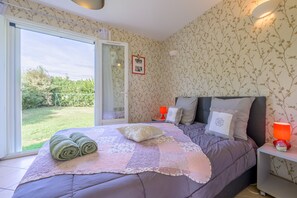 A bedroom with a bed, a nightstand, a window, and a view of the outdoors. - Holiday Home 'Les Demeures Du Soleil - Le Ventoux' with Pool, Wi-Fi and Air Conditioning (Piolenc)