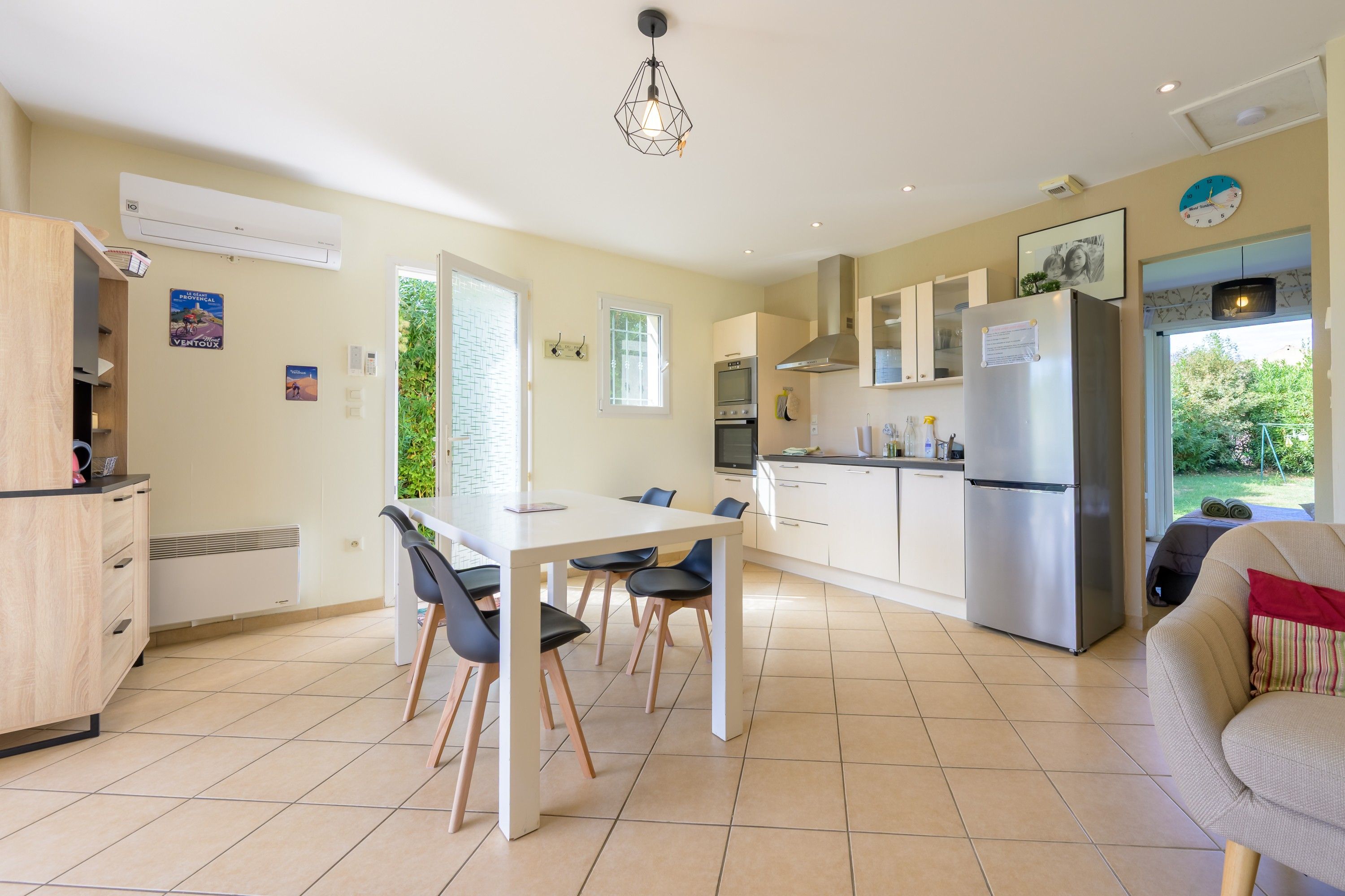 A modern kitchen with a dining area, a built-in oven, a refrigerator, and a window providing natural light.