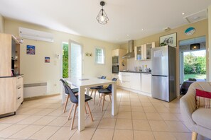 A modern kitchen with a dining area, a built-in oven, a refrigerator, and a window providing natural light. - Holiday Home 'Les Demeures Du Soleil - Le Ventoux' with Pool, Wi-Fi and Air Conditioning (Piolenc)