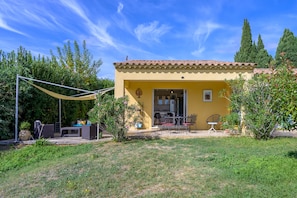 A yellow building with a tiled roof, a patio with outdoor furniture, and a garden with various plants. - Holiday Home 'Les Demeures Du Soleil - Le Ventoux' with Pool, Wi-Fi and Air Conditioning (Piolenc)
