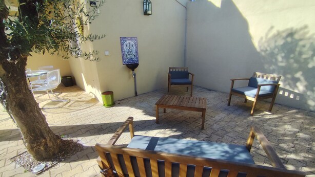Un patio con una panchina di legno, due sedie, un tavolino e un albero.