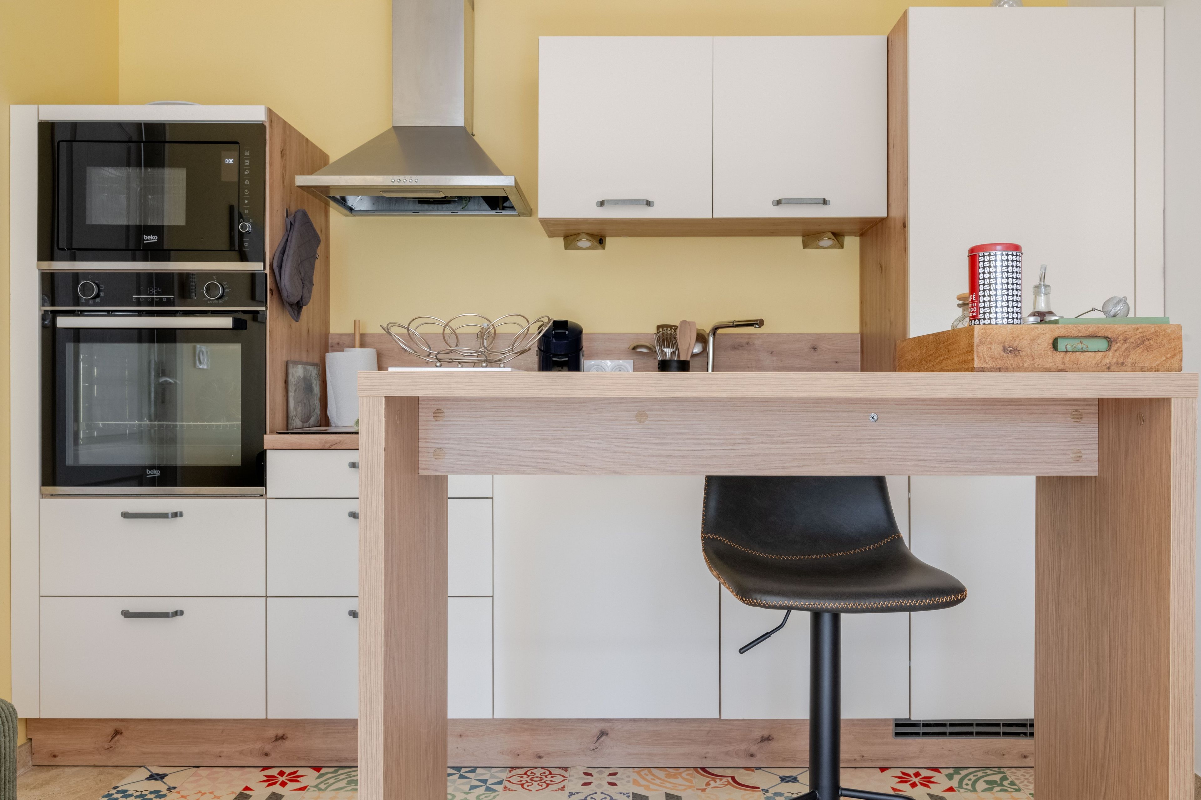 Ett modernt kök med inbyggd ugn, mikrovågsugn och kaffemaskin.