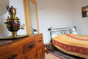 A bedroom with a wooden dresser, a brass decorative item, a bed with a patterned bedspread, and a metal headboard. - Holiday apartment with 3 bedrooms (Meersburg)