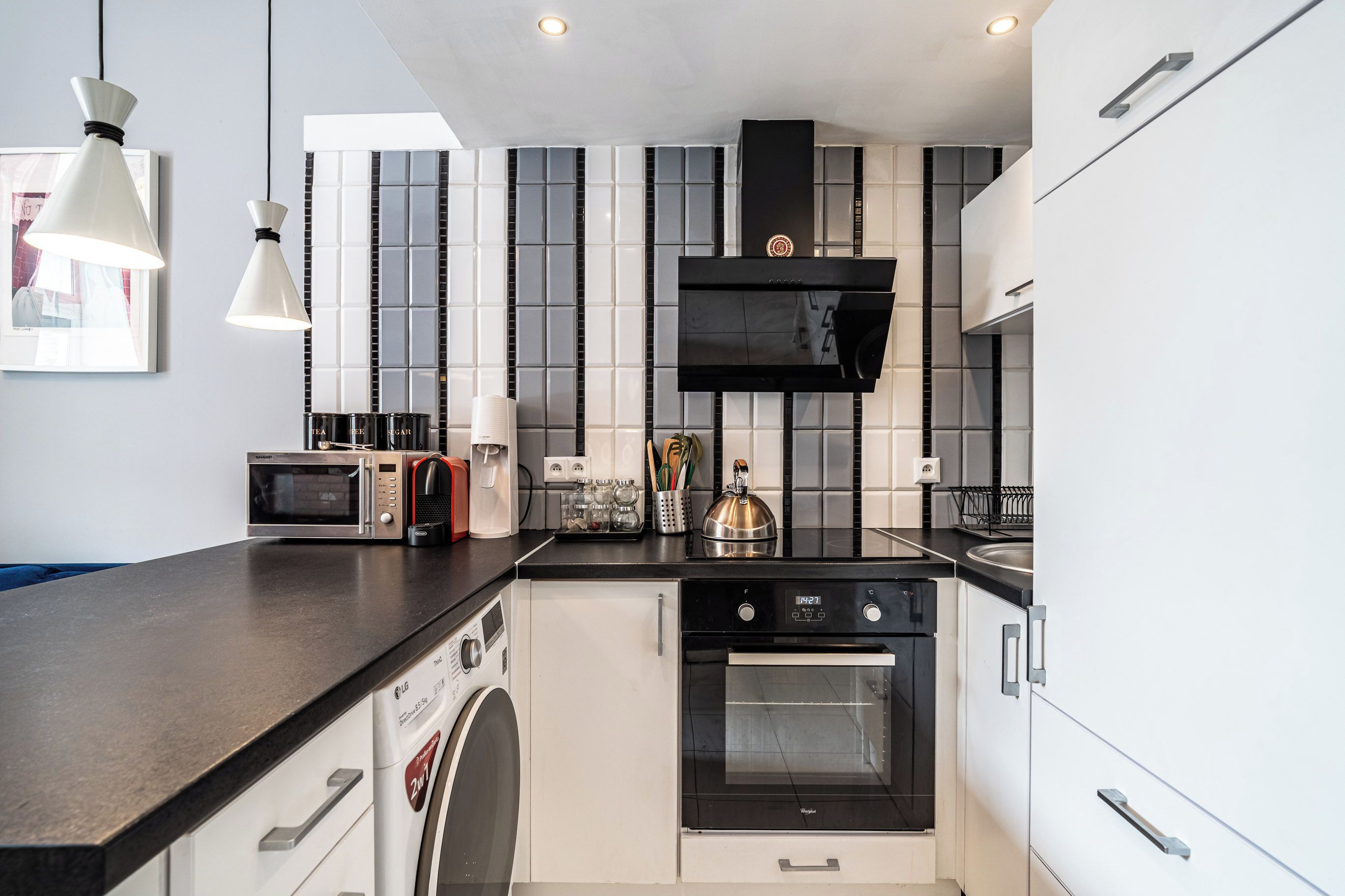 A modern kitchen with a black countertop, stainless steel appliances, and a tiled backsplash.