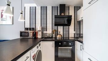A modern kitchen with a black countertop, stainless steel appliances, and a tiled backsplash.