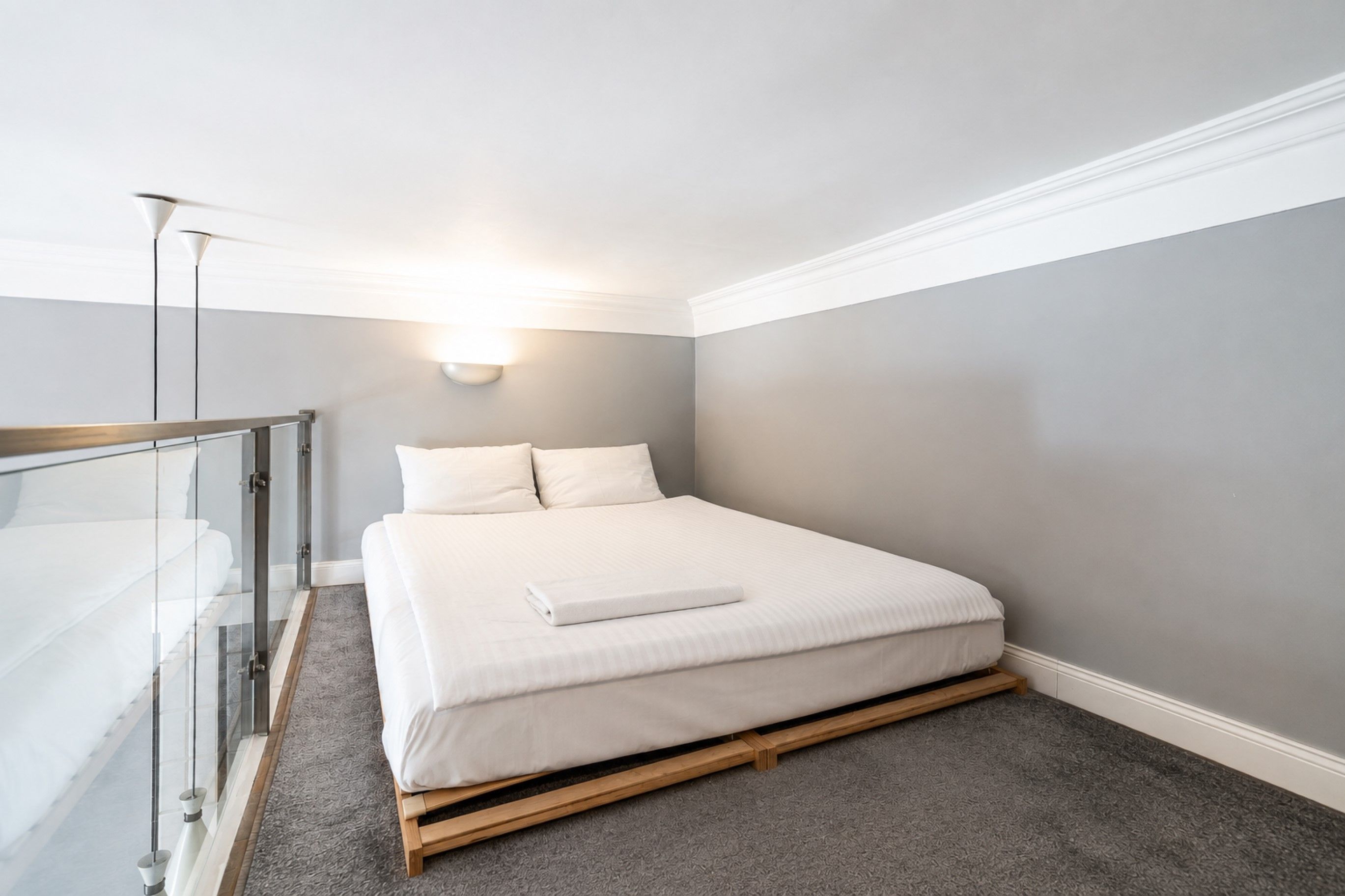 A bedroom with a bed, a bedside table, a lamp, and a glass partition.