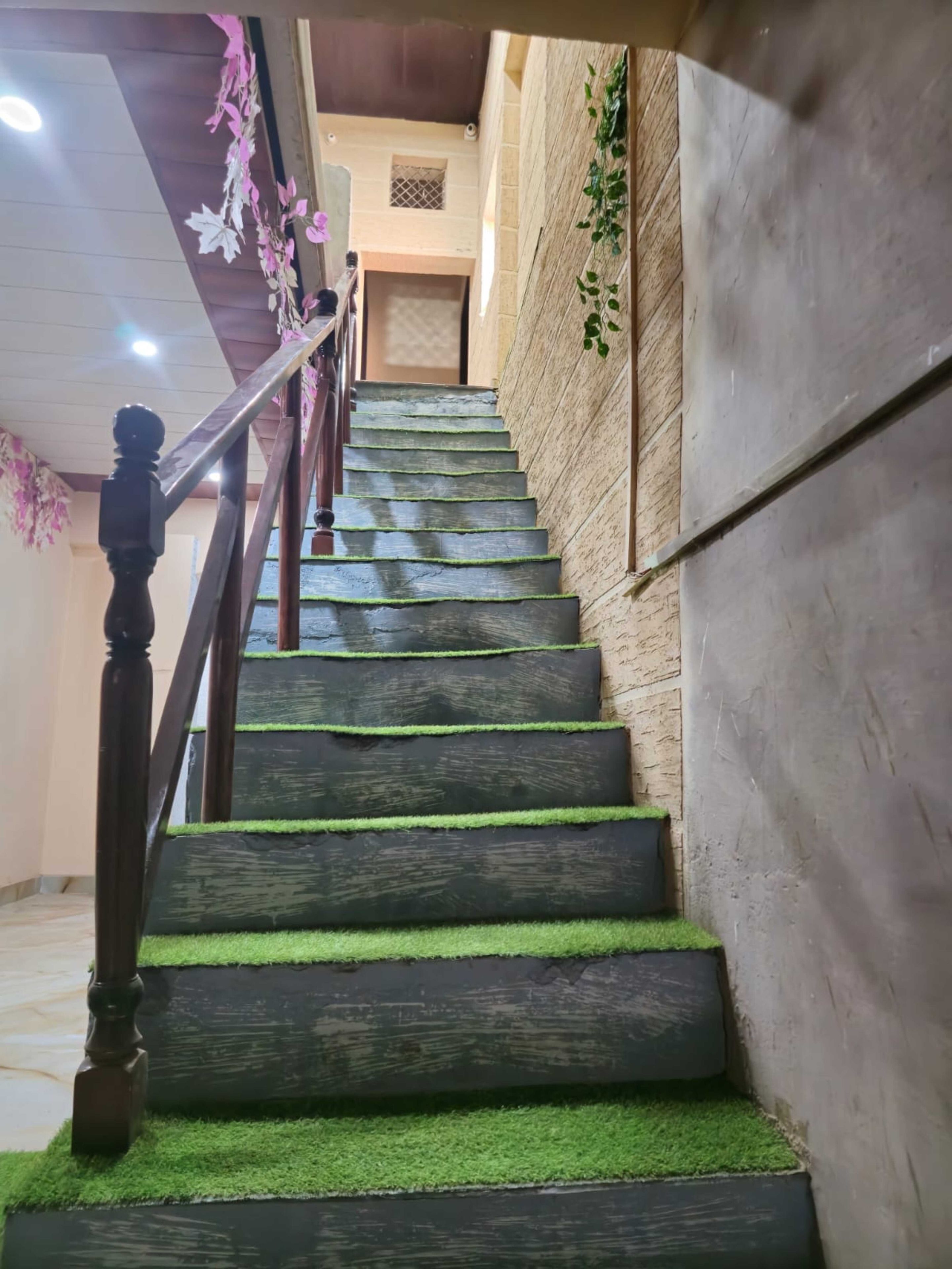 Una escalera de madera con césped artificial verde que lleva a un piso superior.