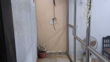 Un pasillo estrecho con una planta en maceta, un ventilador de techo y una ventana con vistas al exterior.