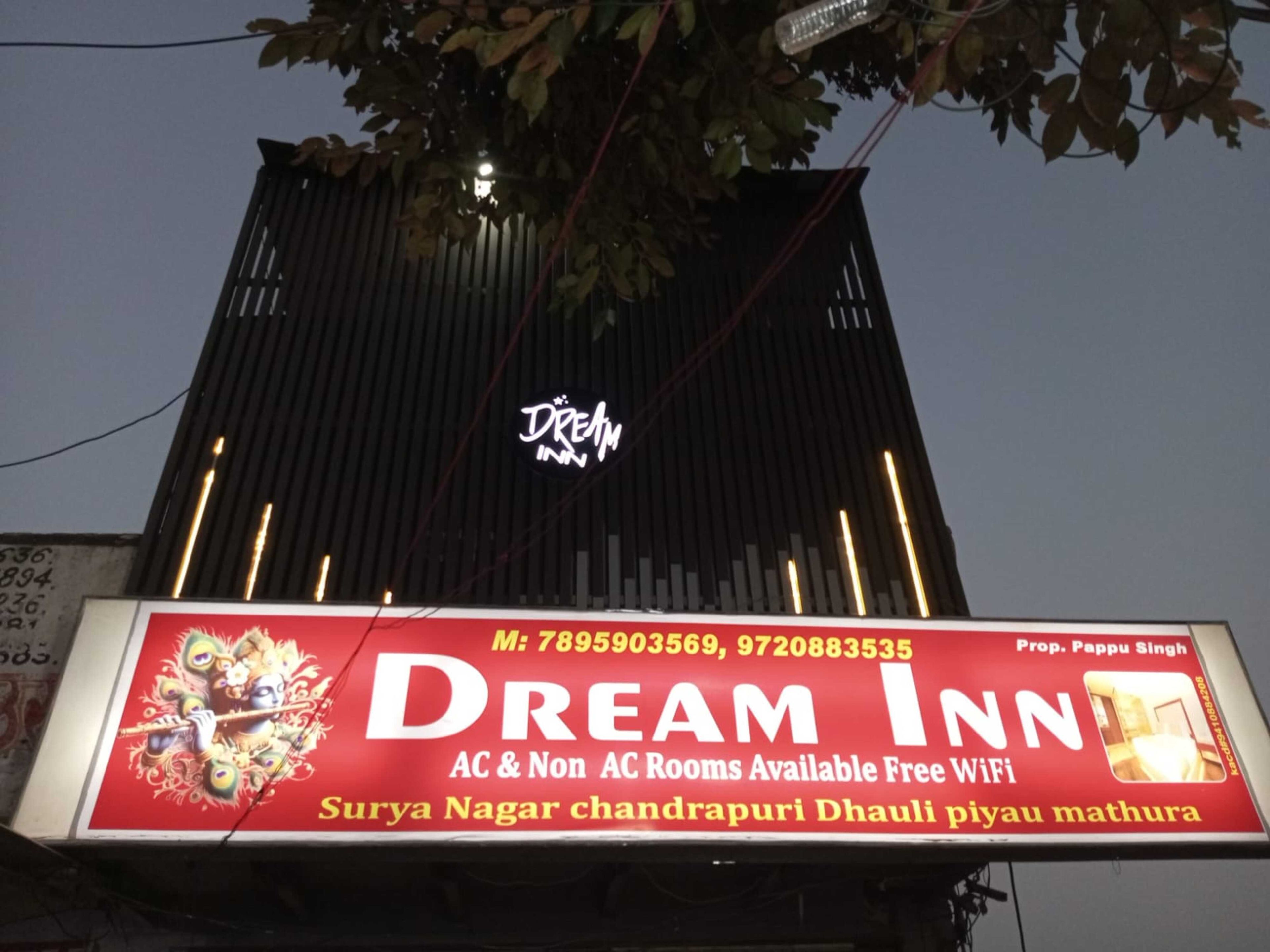 Un letrero de hotel con el nombre 'Dream Inn' y la indicación de habitaciones con aire acondicionado y sin aire acondicionado, WiFi gratuito y números de contacto.