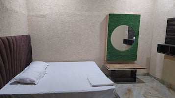 Una habitación con una cama, una mesita, un espejo en la pared y un televisor.