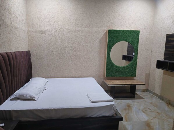 Una habitación con una cama, una mesita, un espejo en la pared y un televisor.