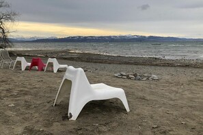 Ein Strand mit Plastikstühlen und einer felsigen Küste.