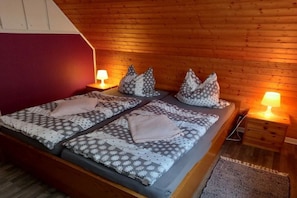 Un lit double avec une literie et des oreillers à motifs, des murs en bois et des lampes de chevet.