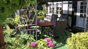 An outdoor patio with a table and chairs, surrounded by greenery and plants. - Holiday apartment with 3 bedrooms (Olsberg-Elpe)