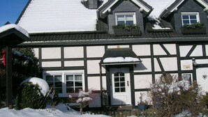 A traditional half-timbered house with a snow-covered roof and a white door. - Holiday apartment with 3 bedrooms (Olsberg-Elpe)