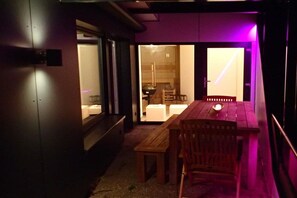 An interior space with a wooden table and chairs, a bench, and a view through a glass door into a room with a white sofa and a lamp. - Holiday apartment with 1 bedroom (Titisee-Neustadt)