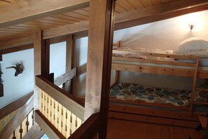 A wooden bunk bed with a patterned mattress and a pillow, a wooden railing, and a wall-mounted light fixture. - Holiday apartment with 1 bedroom (Titisee-Neustadt)