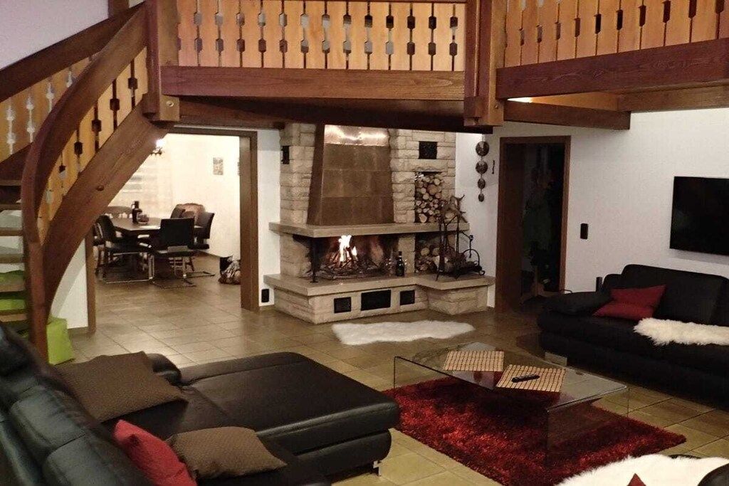 Una sala de estar con chimenea, una escalera y un comedor.