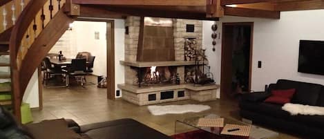Una sala de estar con chimenea, una escalera y un comedor.