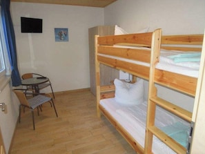 Una habitación pequeña con una cama litera, una mesa y una silla.