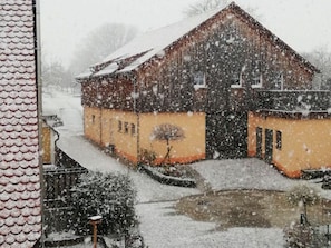 A snow-covered building with a sloped roof and a small pond in front. - 3 - Schuepferlingshof (Kunreuth)