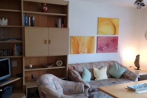 A living room with a sofa, a television, and a bookshelf. - Holiday apartment with 2 bedrooms (Walchensee)