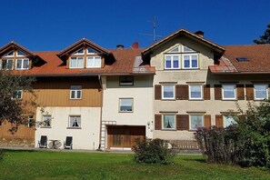 Een rij twee verdiepingen tellende huizen met een garage, een schotelantenne en een kleine tuin.