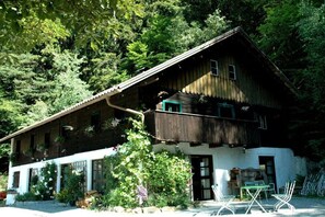 Eine Holzhütte mit einem Balkon, umgeben von dichtem Wald.