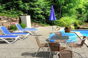 Ein Poolbereich mit Liegestühlen, einem Tisch und einem blauen Sonnenschirm.