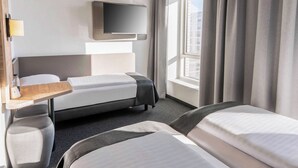 A hotel room with a bed, a desk, a TV, and a window with curtains. - B&B HOTEL Fürth-Hardhöhe (Fürth)