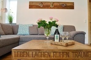 A living room with a wooden coffee table, a sofa, and a wall-mounted decoration. - Holiday apartment with 1 bedroom (Fischen)