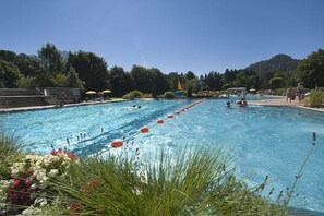 Une piscine avec plusieurs couloirs, entourée de verdure et sous un ciel dégagé.