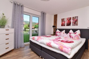 A bedroom with a bed, a dresser, a nightstand, and a window with curtains. - Holiday apartment with 1 bedroom (Fischen)
