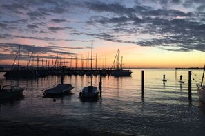 A marina with boats docked at the pier, calm water, and a sunset sky. - 1 in the Walser country house (Wasserburg)