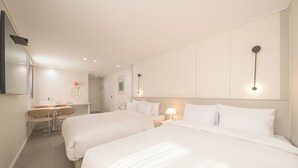 Habitación de hotel con dos camas, un escritorio, una silla y un espejo.