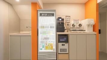 A kitchenette area with a refrigerator, coffee machines, and a microwave.