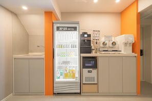A kitchenette area with a refrigerator, coffee machines, and a microwave.