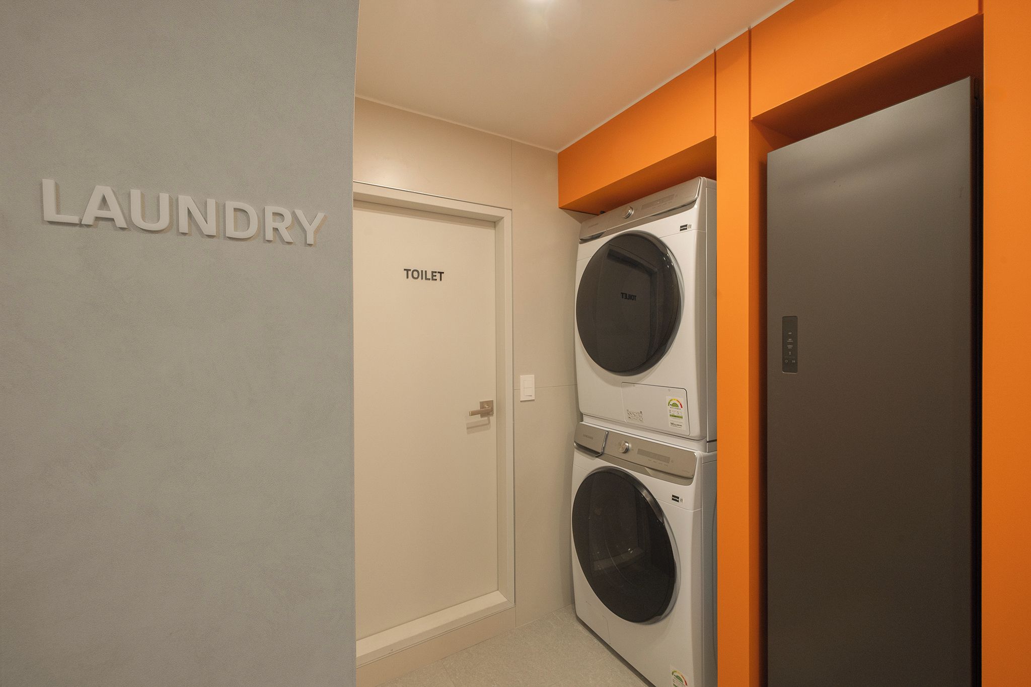 A laundry room with a door labeled 'TOILET' and a washing machine.