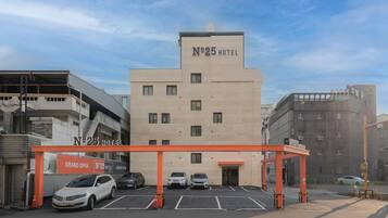 A hotel with a sign reading 'N°25 HOTEL' and a covered parking area with several cars.