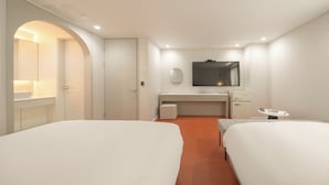 Quarto de hotel com duas camas, escrivaninha, espelho e minibar.
