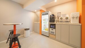 Una habitación de hotel con minibar, refrigerador, cafetera y basurero.