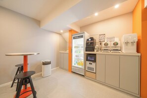 Hotellihuone, jossa on minibaari, jääkaappi, kahvinkeitin ja roskakori.