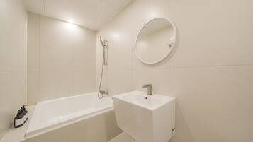 A bathroom with a bathtub, a sink, and a mirror.