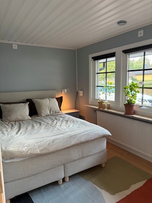 Ett sovrum med en säng, sänglampor, ett fönster med utsikt och ett element.