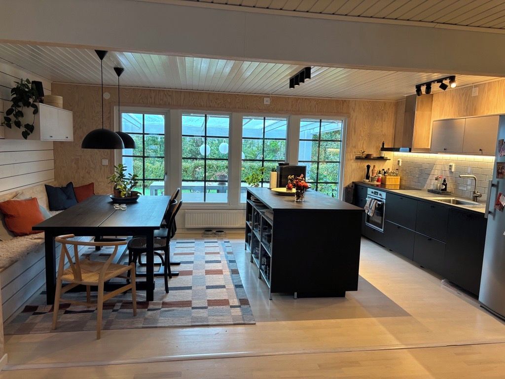 Ett modernt kök med matplats, stora fönster och en inbyggd ugn.