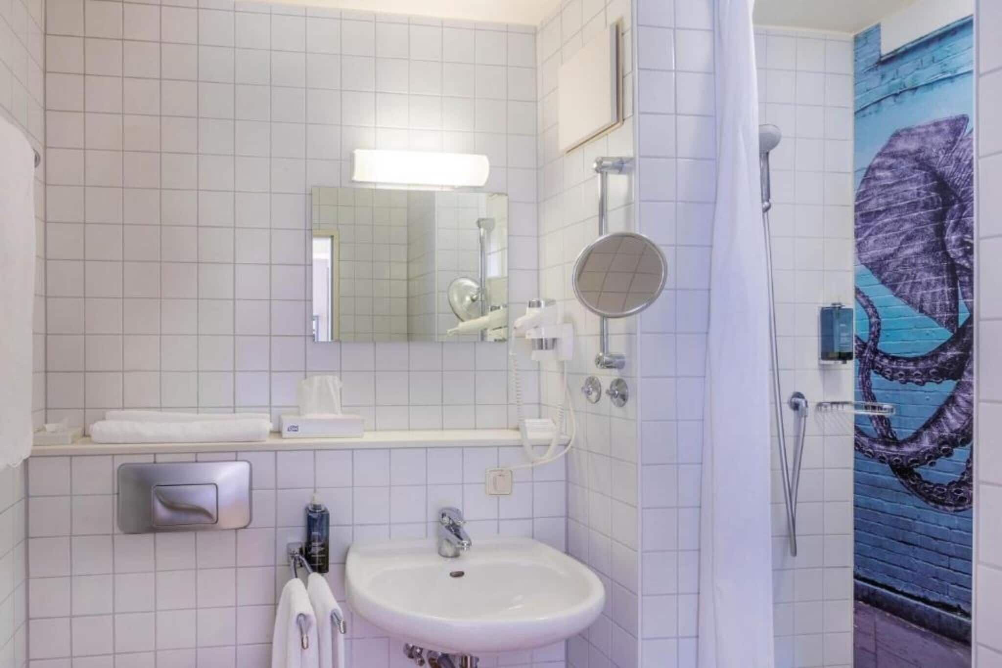 A bathroom with a sink, mirror, towel rack, and a shower.