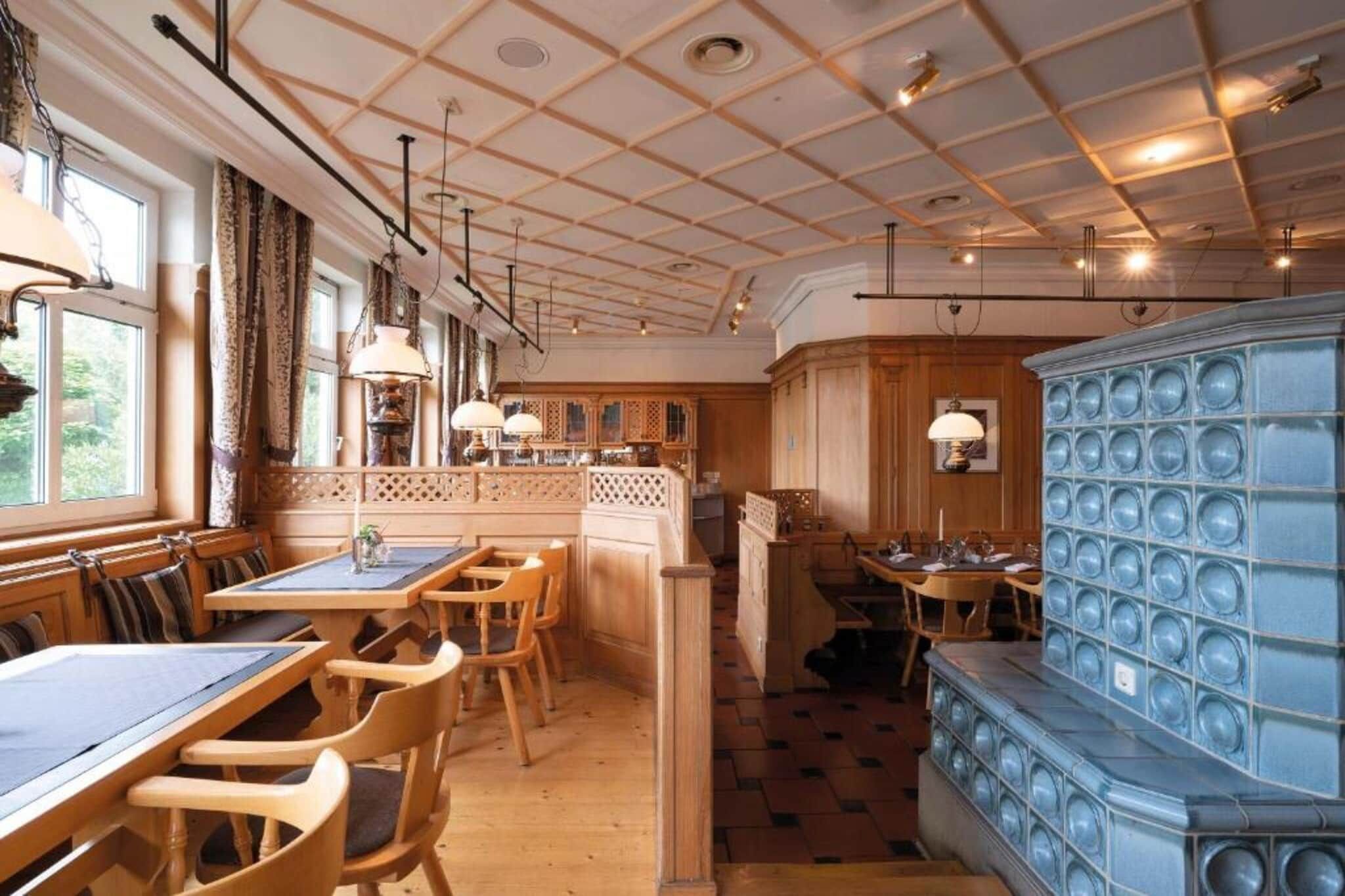Een restaurant met houten meubels, hanglampen en een versierd plafond.