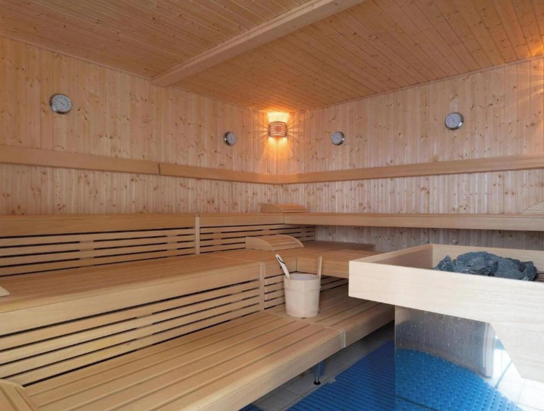 Una sauna con panche in legno, un catino e una vasca in pietra.