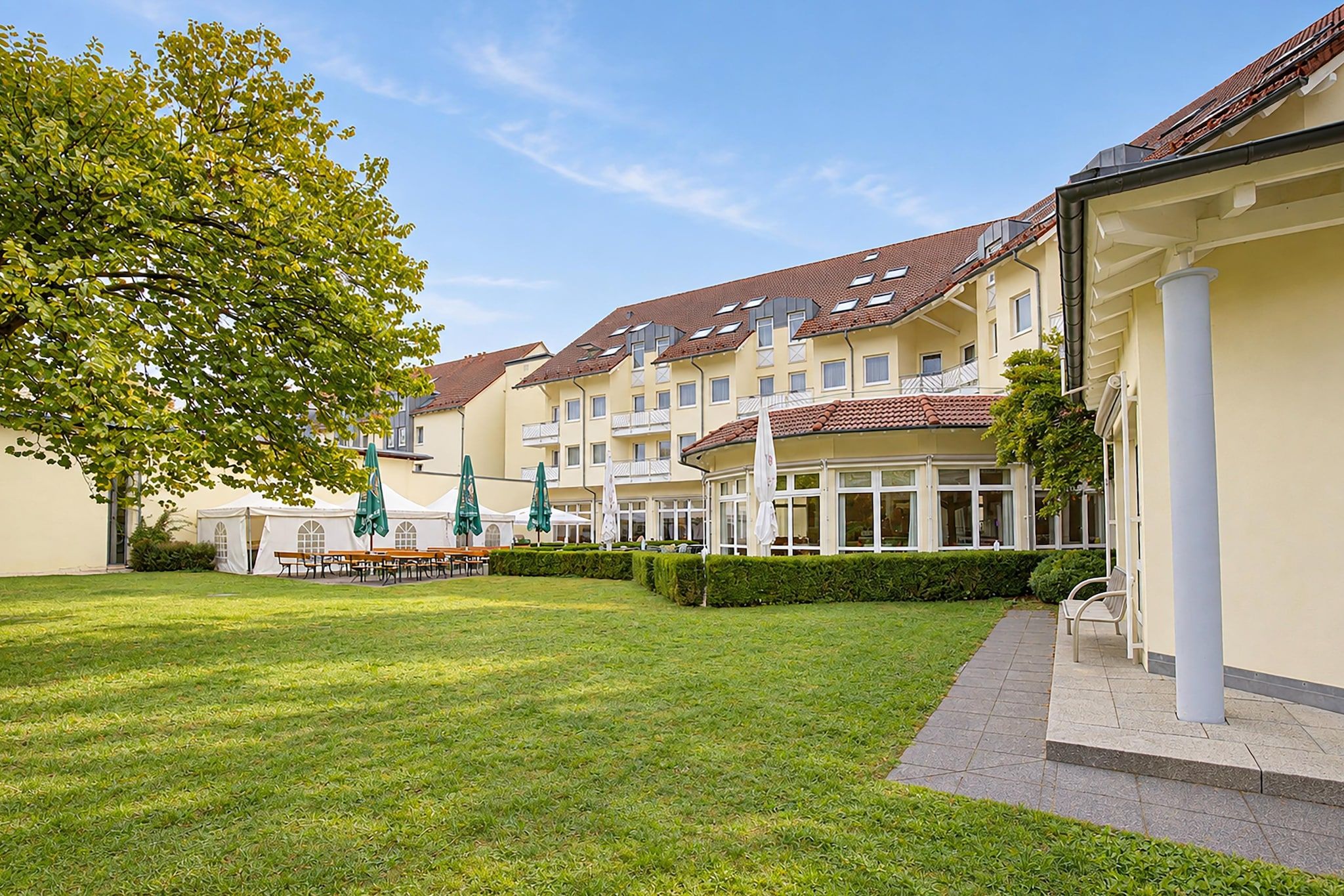 Ein Innenhof mit Rasenfläche, Gartenmöbeln und einem Gebäude mit zahlreichen Fenstern und Balkonen.